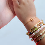 Child's hand wearing multiple colorful bracelets on a light background