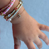 Hand wearing multiple bracelets on a light blue background