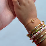 Child's hand wearing multiple colorful bracelets on a light background
