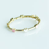 Gold bracelet with colorful beads on a light blue background