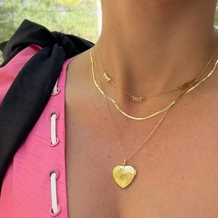 Diamond heart locket necklace in gold-plated sterling silver, elegant lifestyle image with pink dress and layered gold chains
