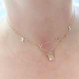 Woman breastfeeding a baby with a necklace on, indoors.