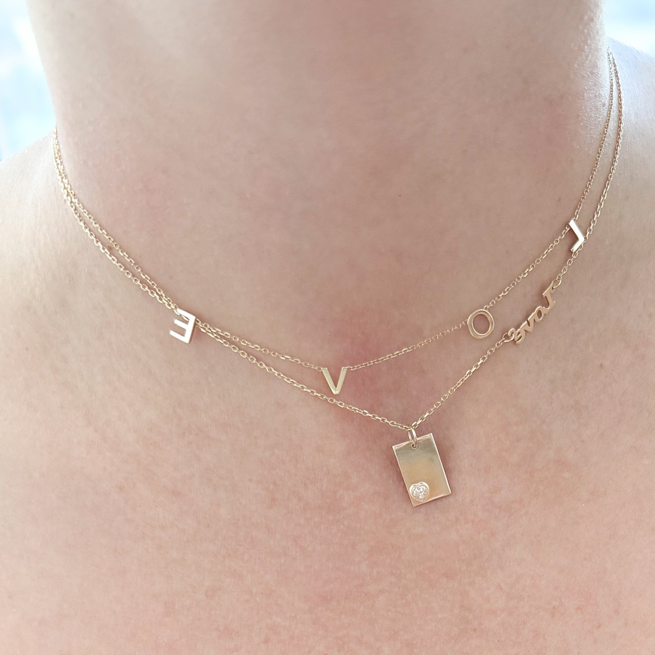 Woman breastfeeding a baby with a necklace on, indoors.