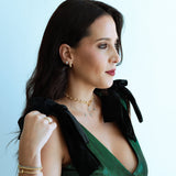 Woman wearing a green dress with black bow detail against a light blue background