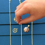 Hand holding a necklace with a basketball pendant against a blue textured background