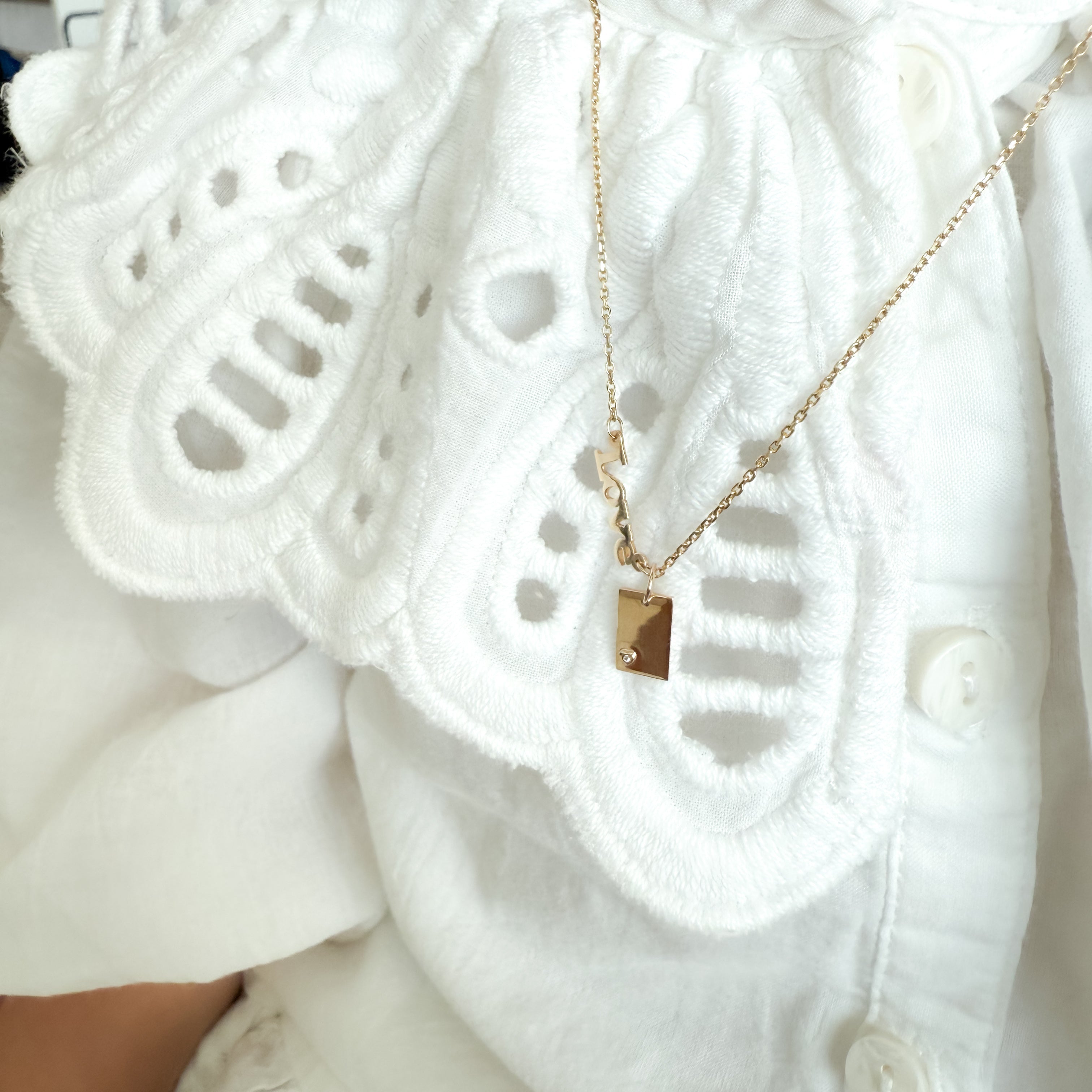 Gold necklace with a pendant on a white lace garment