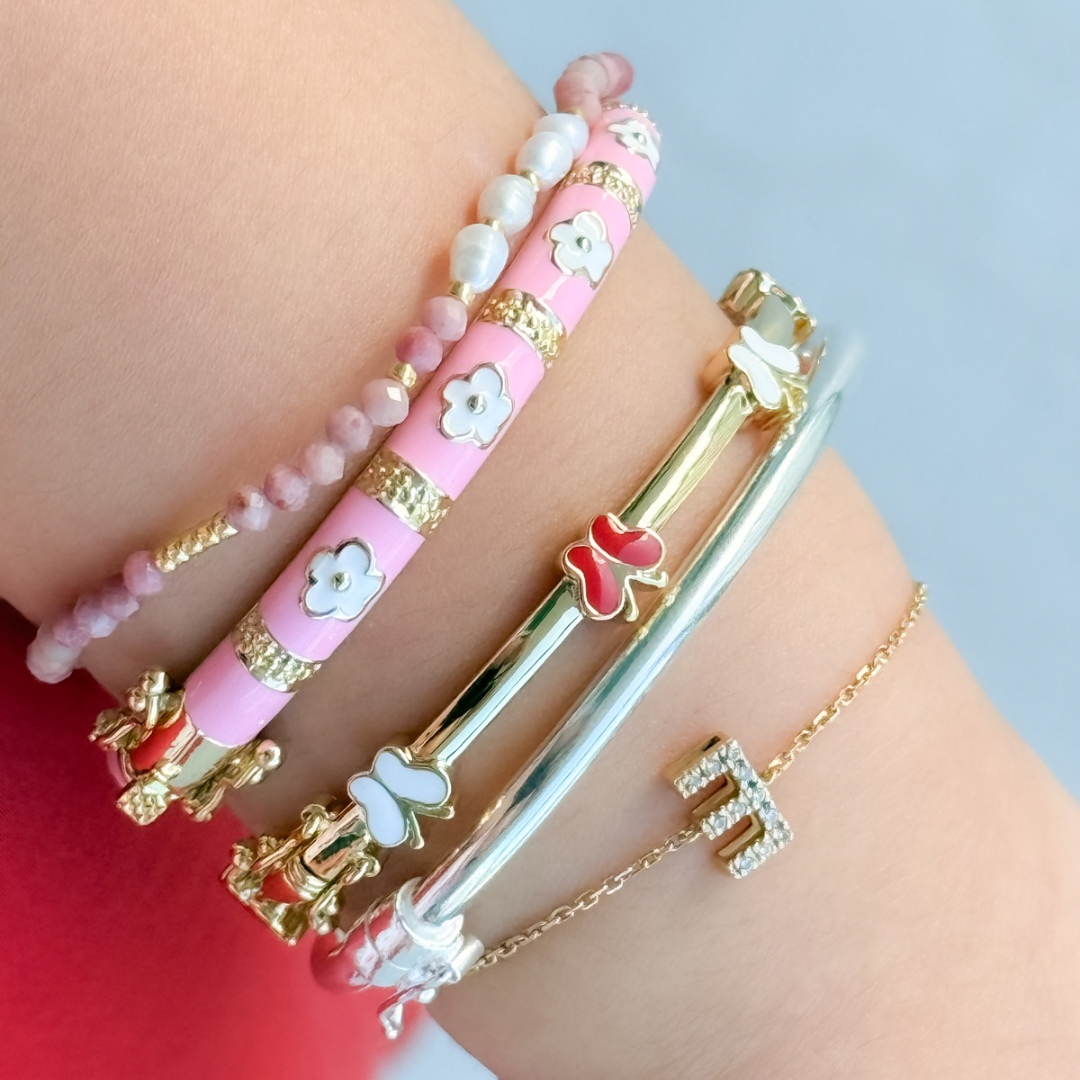 Close-up of a wrist wearing multiple colorful bracelets on a light blue background