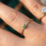Elegant green emerald cut CZ ring in 14K yellow gold worn on hand outdoors