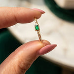 14K gold emerald-colored ring with zirconia accents held between fingers in natural light, featuring a delicate minimalist fine jewelry design.