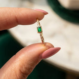14K gold emerald-colored ring with zirconia accents held between fingers in natural light, featuring a delicate minimalist fine jewelry design.