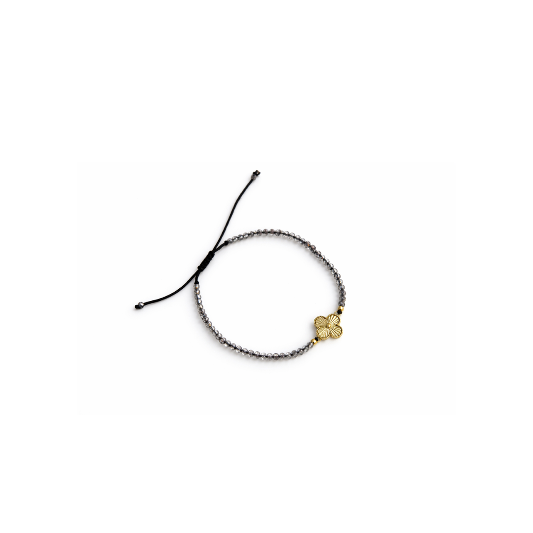 Adjustable black macrame bracelet with smokey quartz beads and 14K gold clover charm on white background
