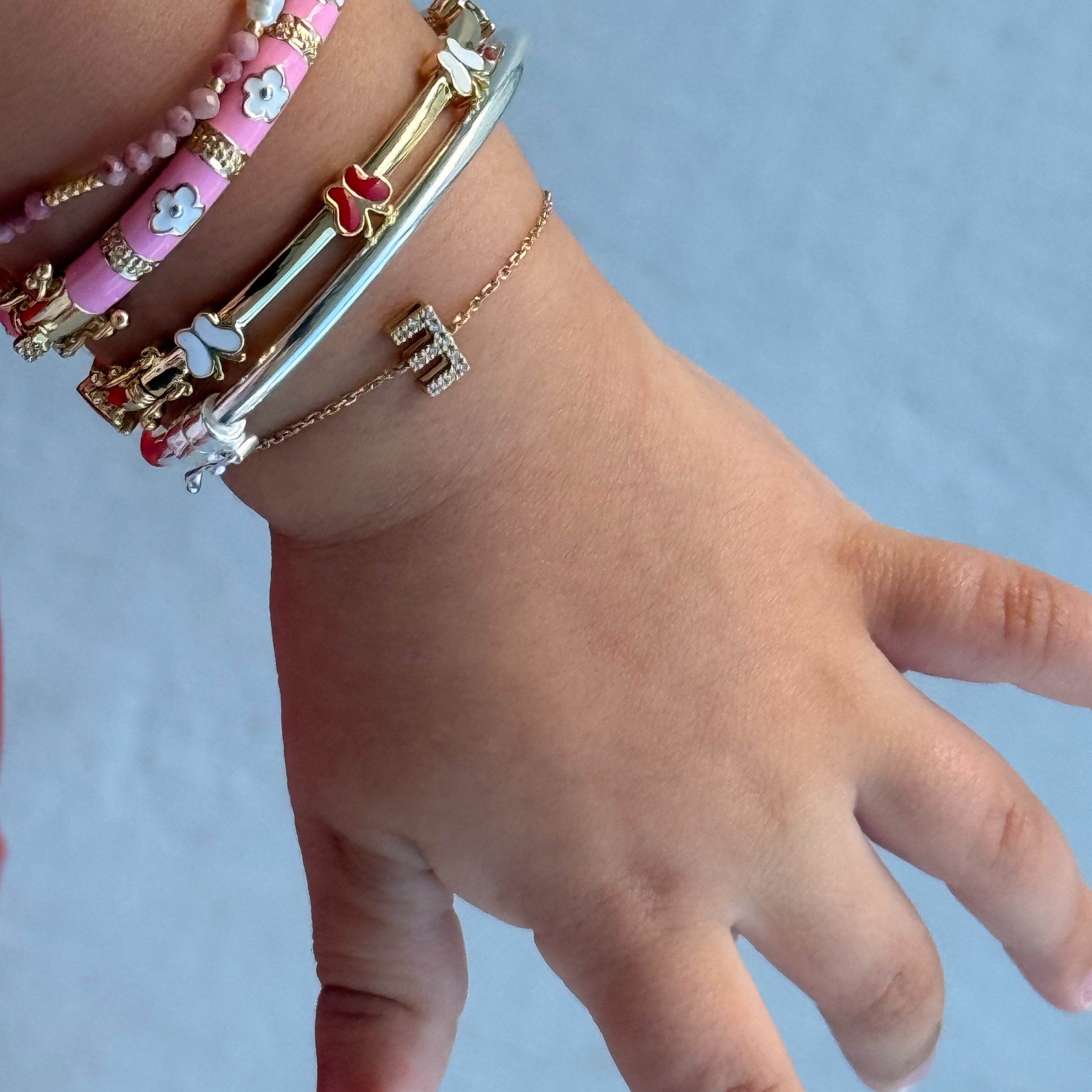 Hand wearing multiple bracelets on a light blue background