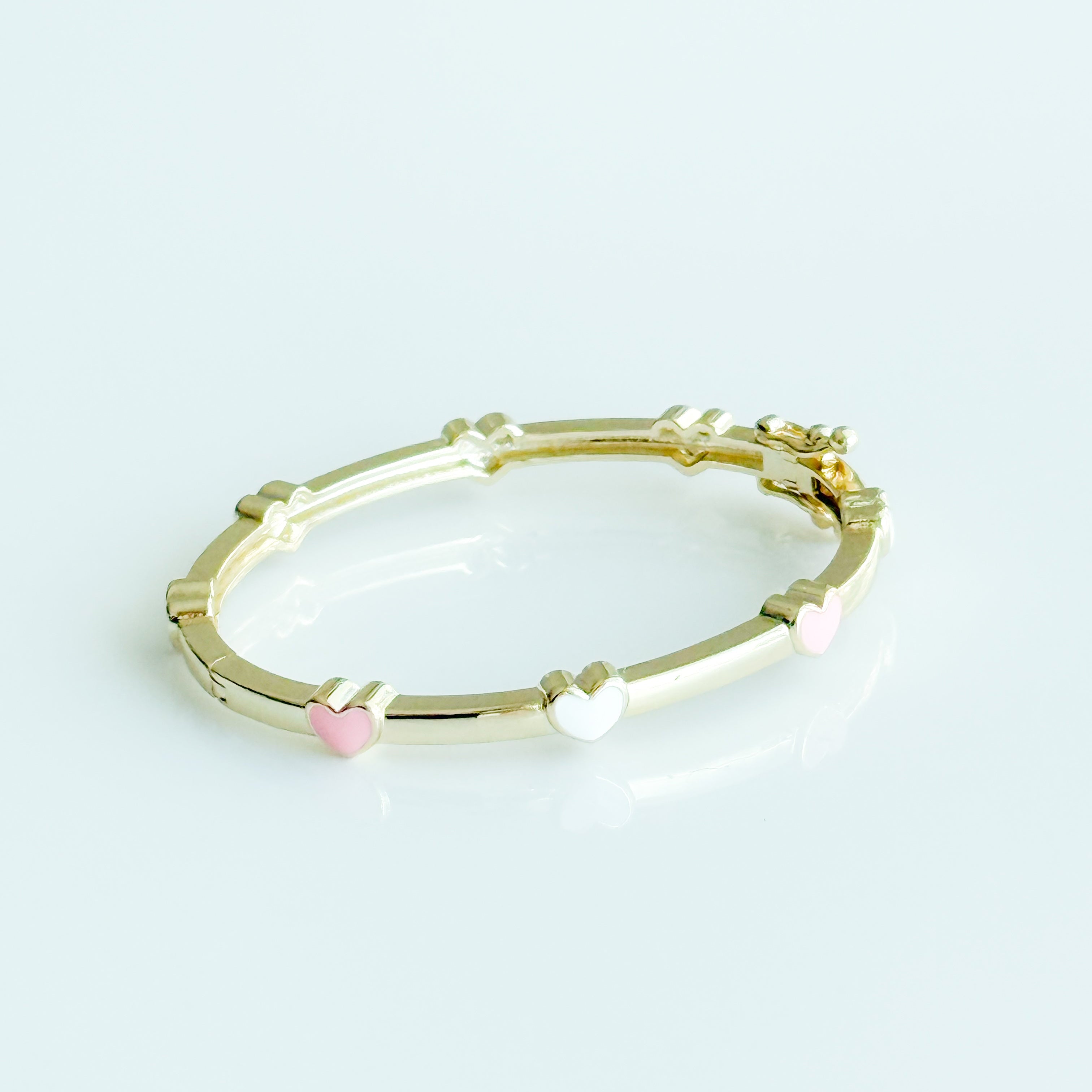 Gold bracelet with pink and white beads on a light gray background