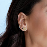 Close-up of a person wearing gold earrings with a blurred background