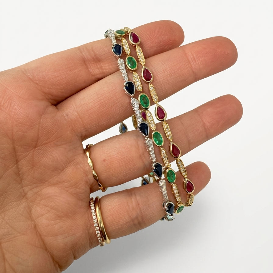 Hand wearing gold bracelets with colorful gemstones on a white background