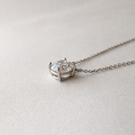 close-up side view of 1 ct certified lab-grown diamond necklace in 14K white gold on soft neutral fabric