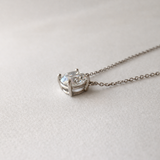 close-up side view of 1 ct certified lab-grown diamond necklace in 14K white gold on soft neutral fabric