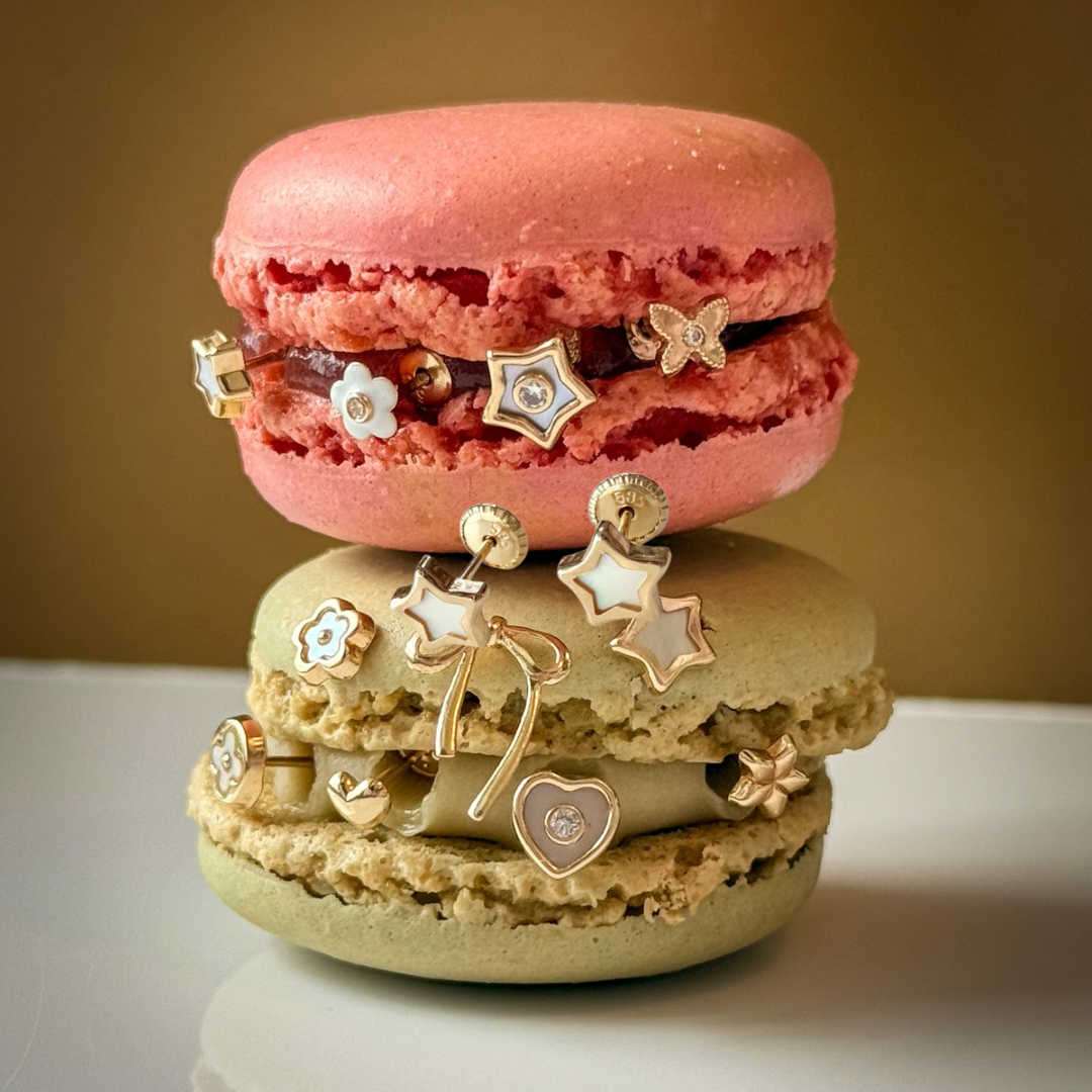 Two macarons stacked with decorative jewelry on a neutral background