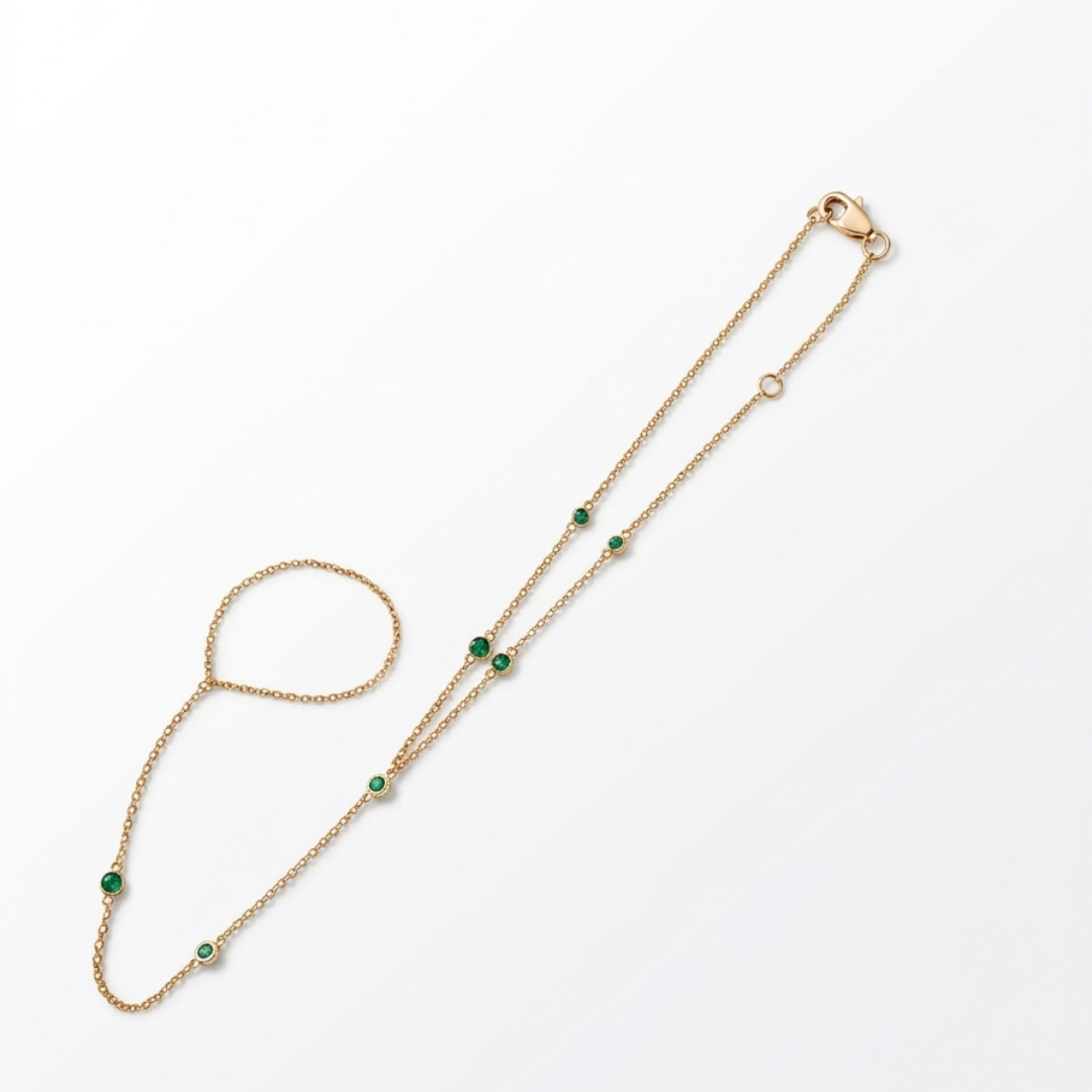 14k gold emerald hand chain bracelet worn on hand outdoors with delicate green gemstones and layered bracelets