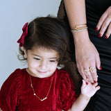 Child in a red dress holding hands with an adult against a light blue background