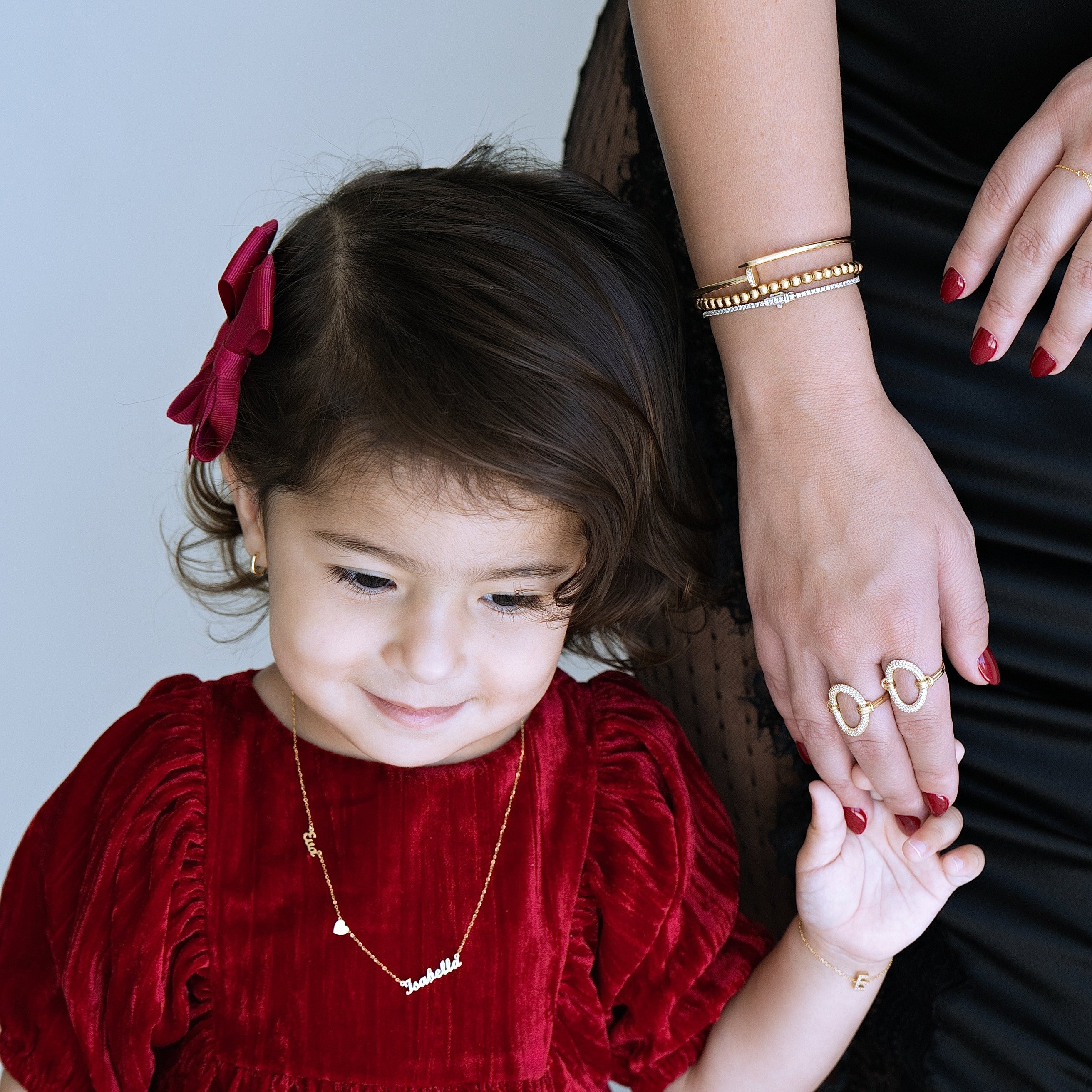 Child in a red dress holding hands with an adult against a light blue background