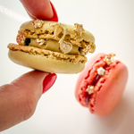 Macaron cookies with decorative elements held by a hand on a white background