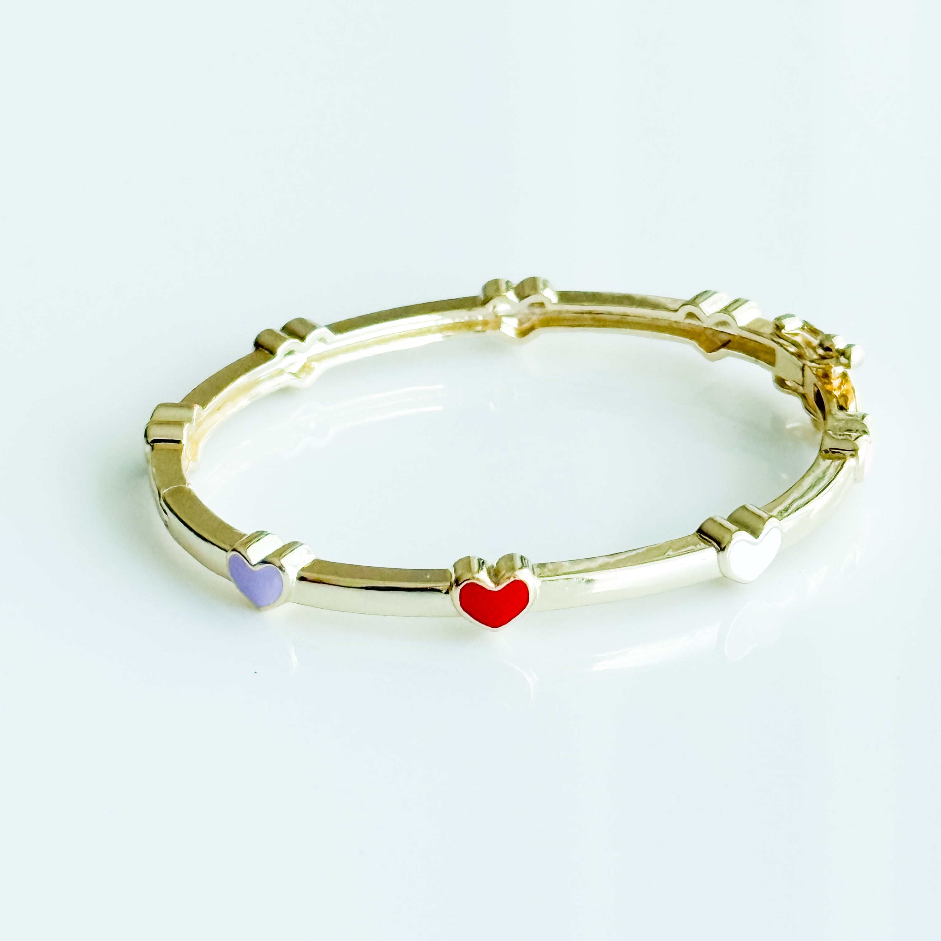 Gold bracelet with heart-shaped charms on a white background