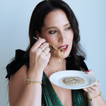 Woman eating from a decorative plate with a spoon against a light blue background