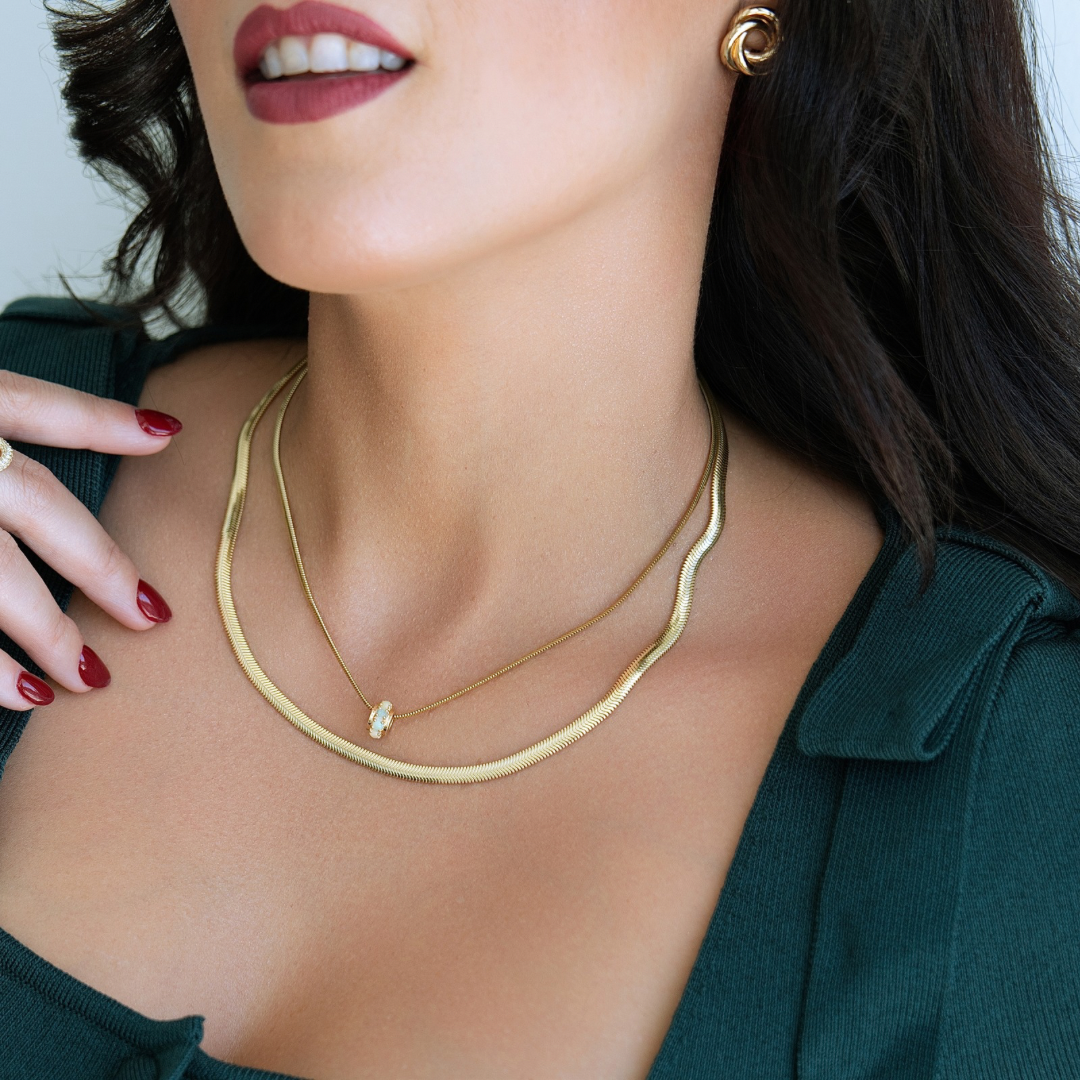 Close-up of a woman wearing a gold necklace and earrings with a blurred background