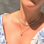 Lifestyle close-up of a 14K solid yellow, white, and rose gold Miraculous Medal pendant necklace in natural sunlight, showcasing the tri-tone finish and brilliant CZ accents.