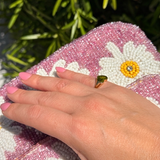 Close-up side angle of a hand wearing a 14K solid yellow gold heart signet ring in natural sunlight.