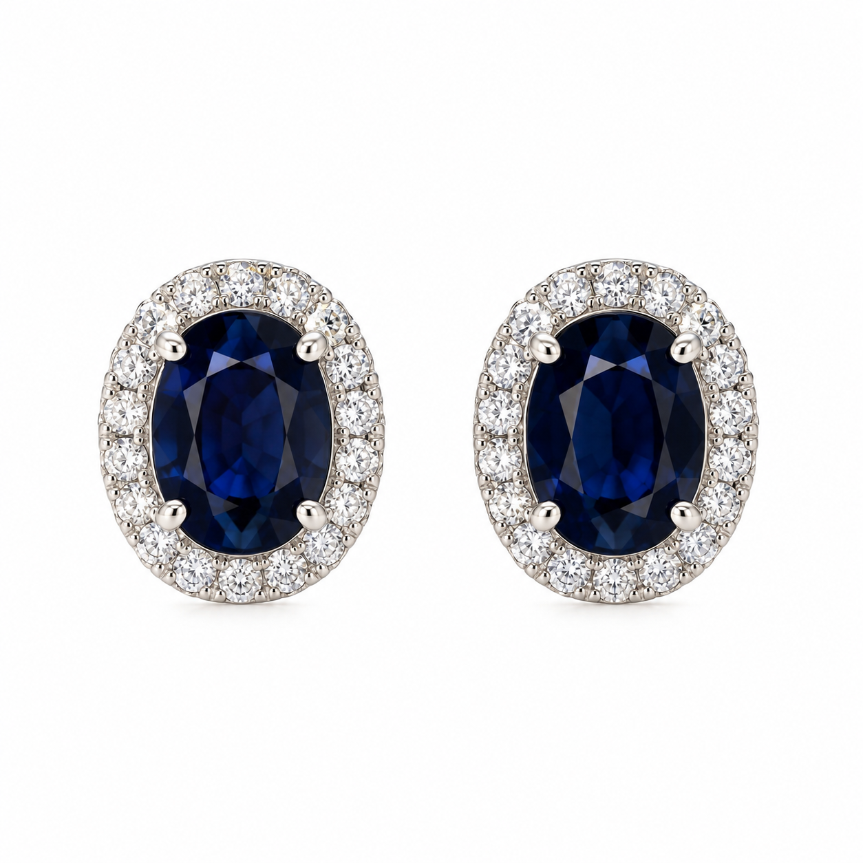 Pair of solid 14K white gold oval natural blue sapphire stud earrings surrounded by sparkling natural pavé diamond halos, front view.