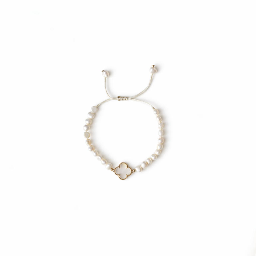 Freshwater pearl bracelet with 14K yellow gold clover detail and adjustable macrame closure on white background