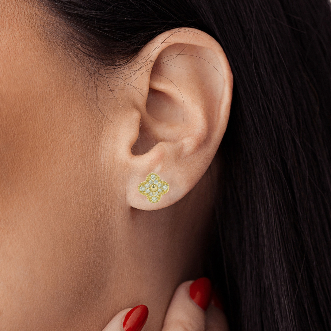 Close-up of a women ear wearing a 14K yellow gold clover stud earrings with natural diamonds