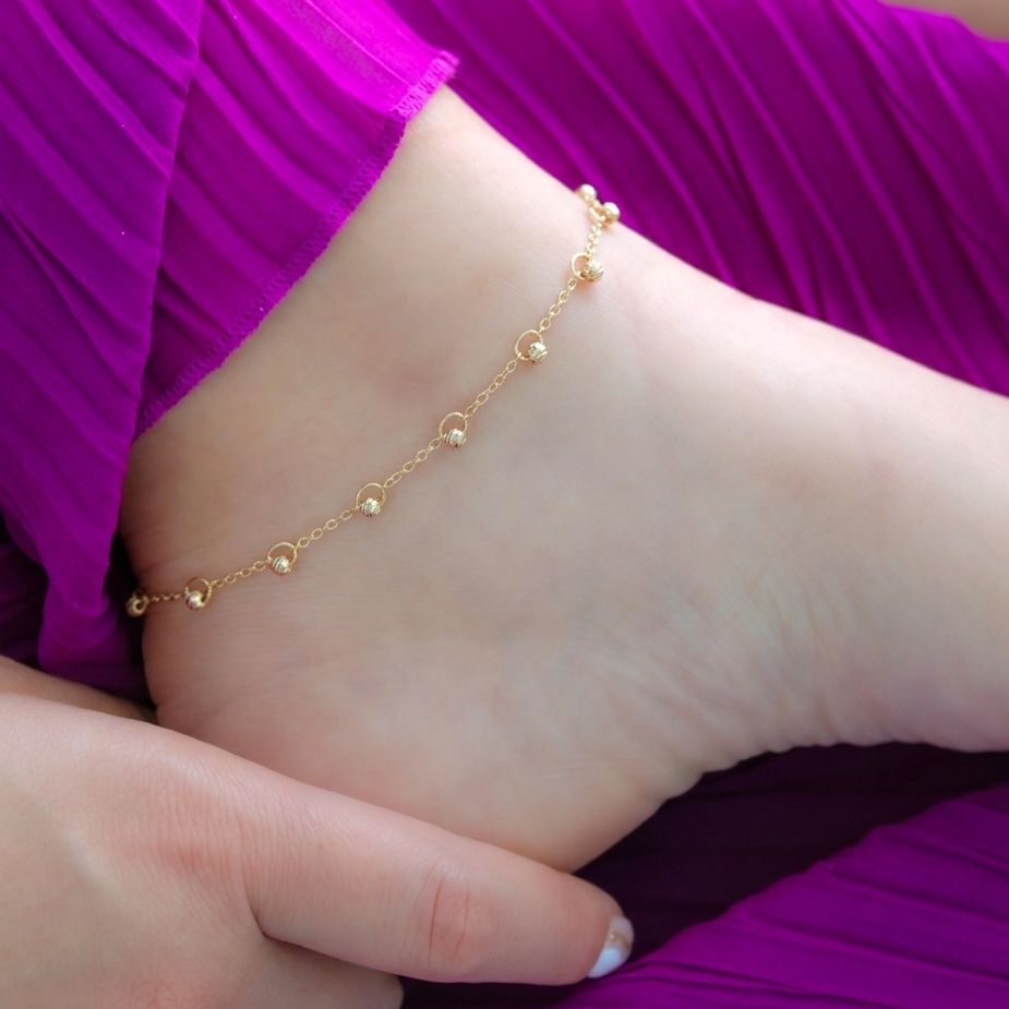 delicate 14k gold anklet with textured beads softly draped on ankle, feminine minimal jewelry