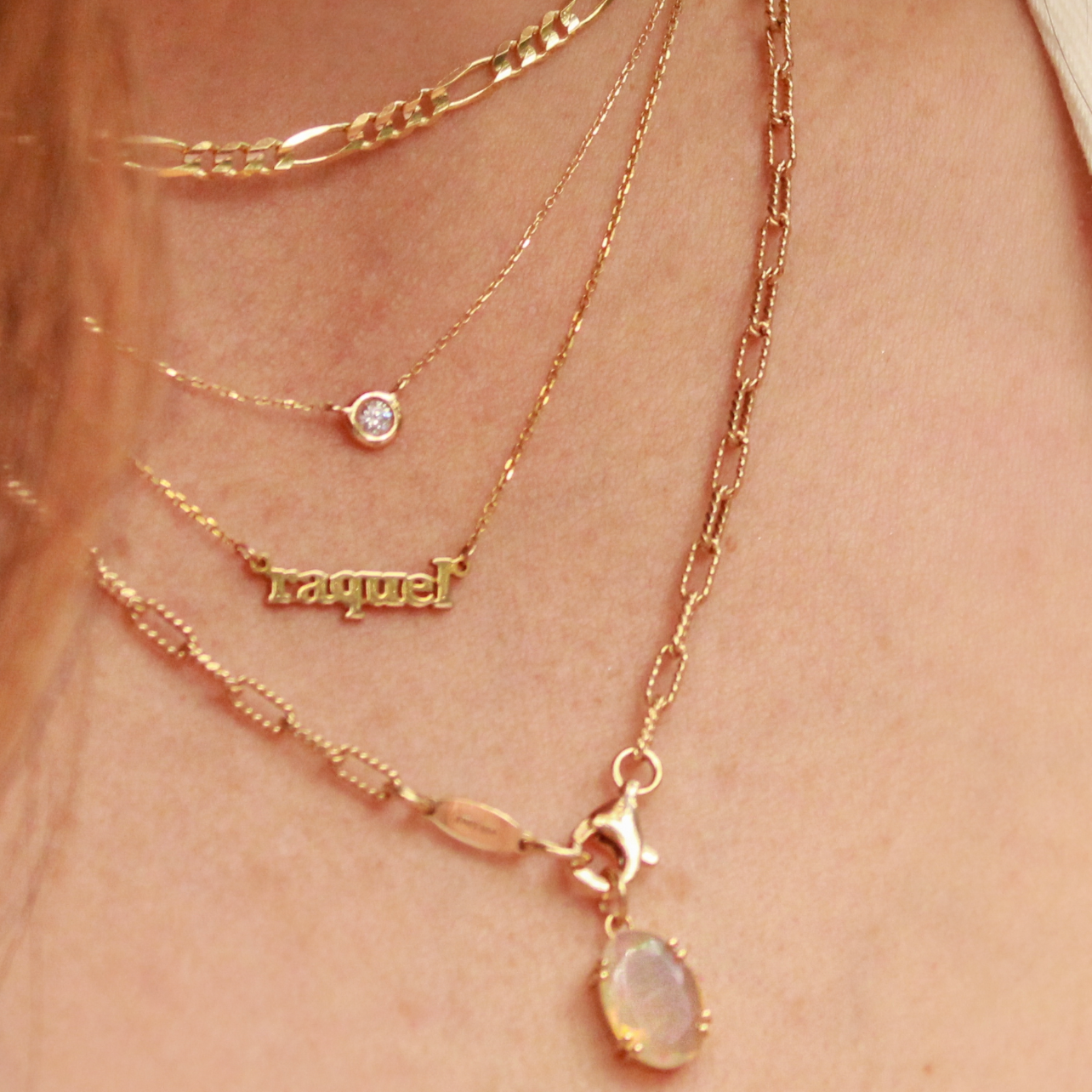 Close-up of a person wearing multiple gold necklaces with a visible brand name.