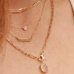 Close-up of a person wearing multiple gold necklaces with a visible brand name.