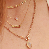 Close-up of a person wearing multiple gold necklaces with a visible brand name.