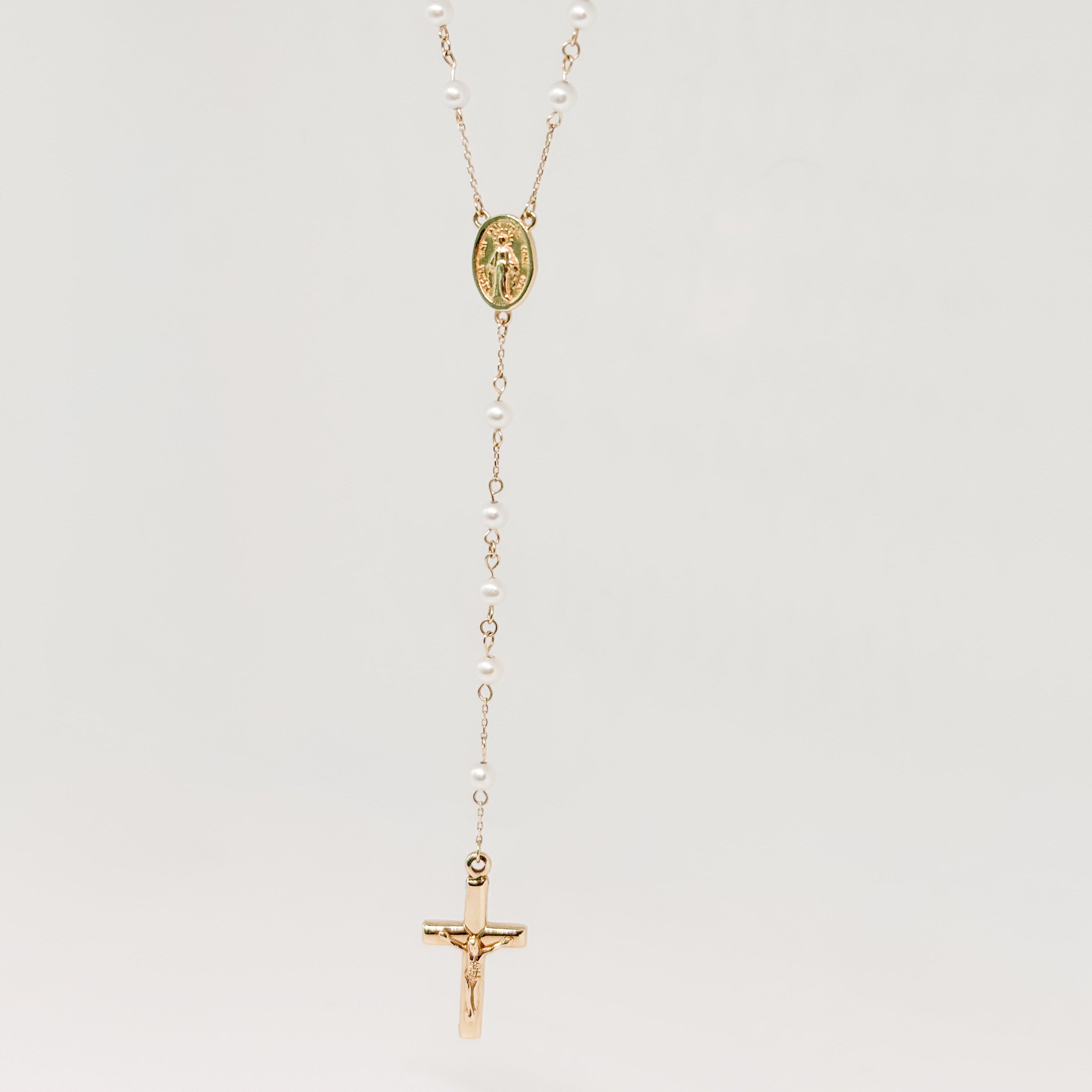 Gold necklace with a cross pendant on a light gray background