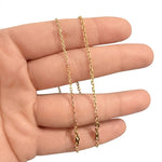 Gold chain held between fingers on a white background. solid 14k yellow gold square cable chain necklace 1.5mm and 2mm minimalist jewelry.