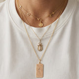 Close-up of a 14K solid yellow gold 24-inch rolo chain necklace featuring layered pendant styling with meaningful gold jewelry and religious charms