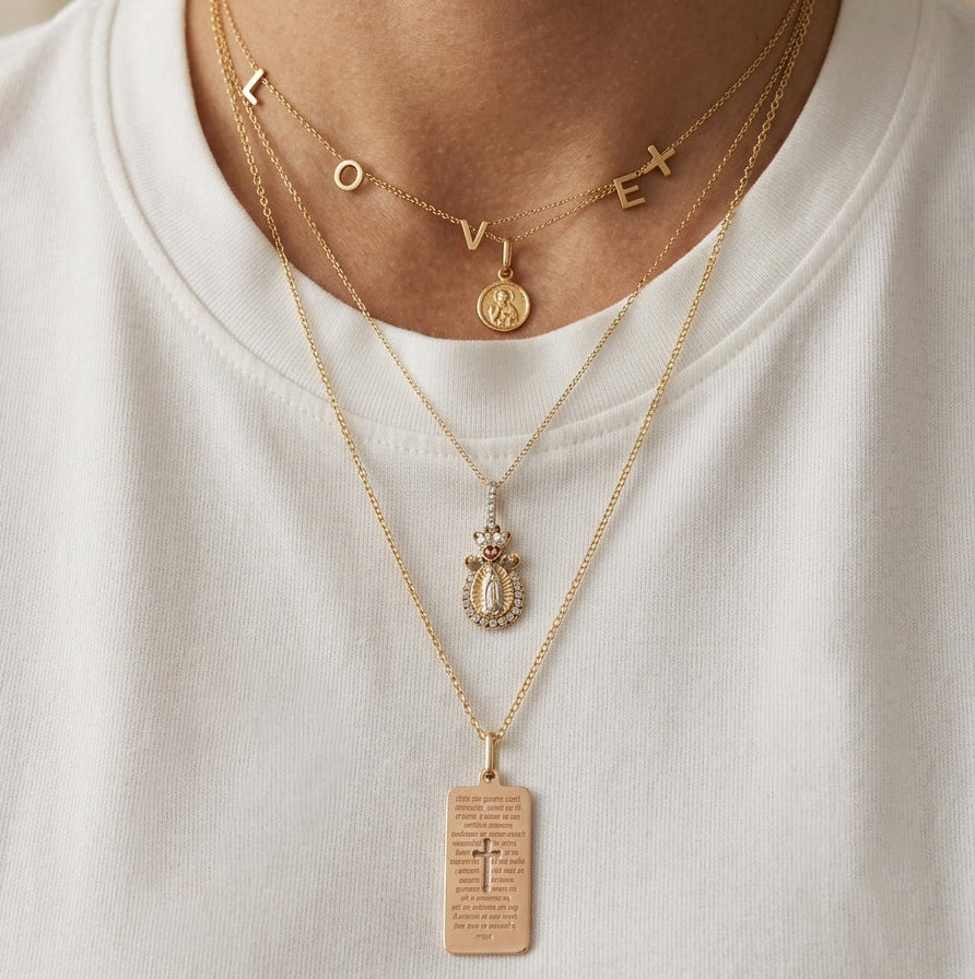Close-up of a 14K solid yellow gold 24-inch rolo chain necklace featuring layered pendant styling with meaningful gold jewelry and religious charms