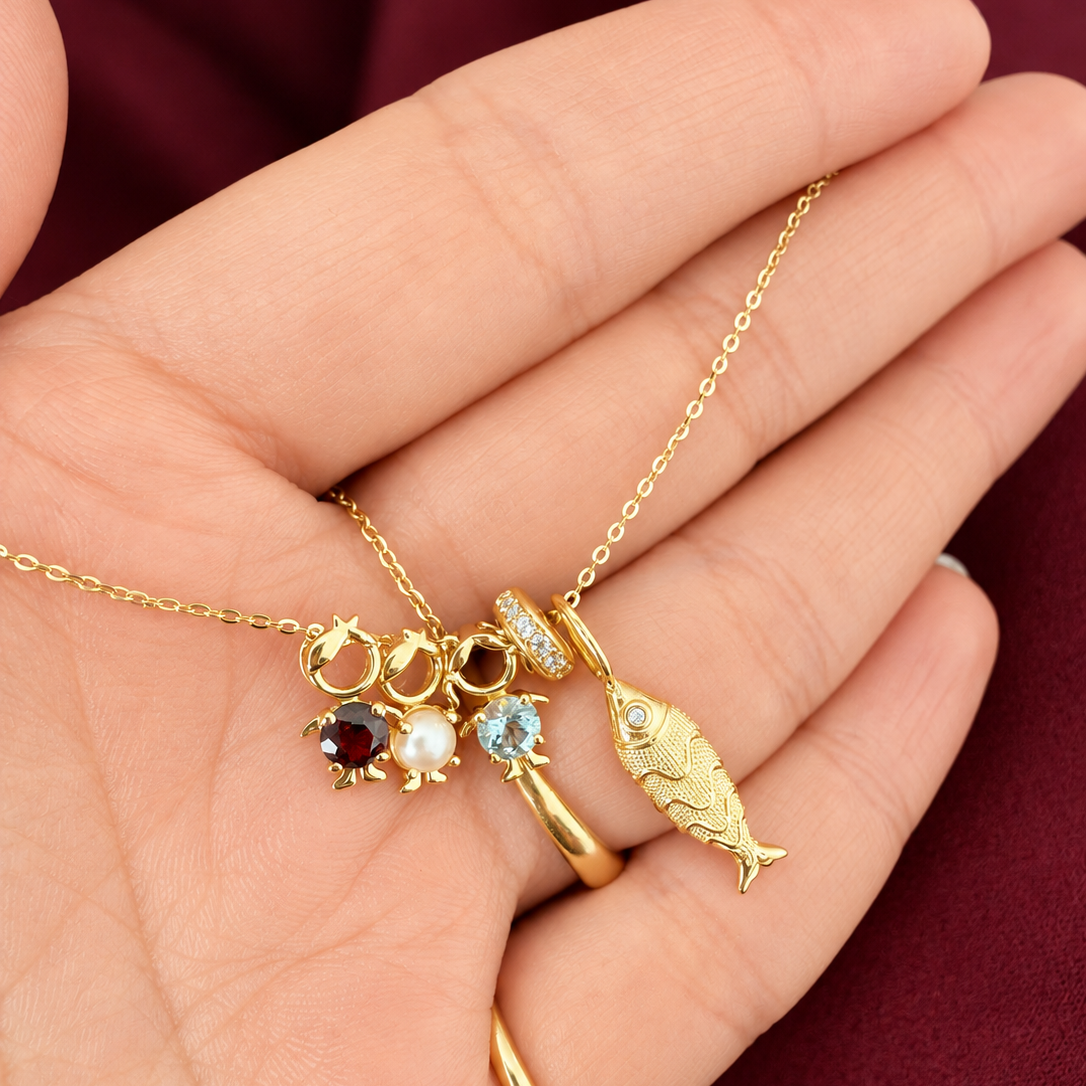 14K solid yellow gold CZ silicone spacer bead styled on a gold necklace with charms, including a textured fish pendant and pavé initial charm.