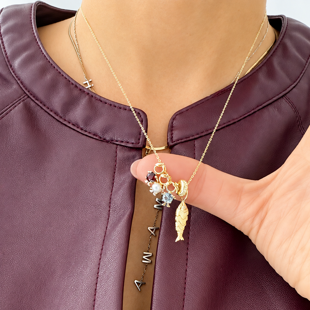 14K solid yellow gold CZ silicone spacer bead styled on a gold necklace with charms, including a textured fish pendant and pavé initial charm.