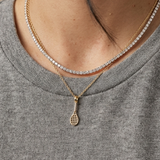 Model wearing a 14K solid yellow gold tennis racket pendant with sparkling clear CZ stones, layered with a tennis necklace, showcasing luxury tennis jewelry and athlete-inspired fine jewelry.