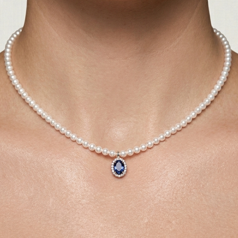 Woman wearing an 18K solid yellow gold pearl necklace featuring 118 cultured pearls and an oval blue sapphire pendant surrounded by a sparkling diamond halo.