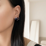 Woman wearing 18K yellow gold natural blue sapphire dangle earrings featuring oval and round sapphire gemstones.