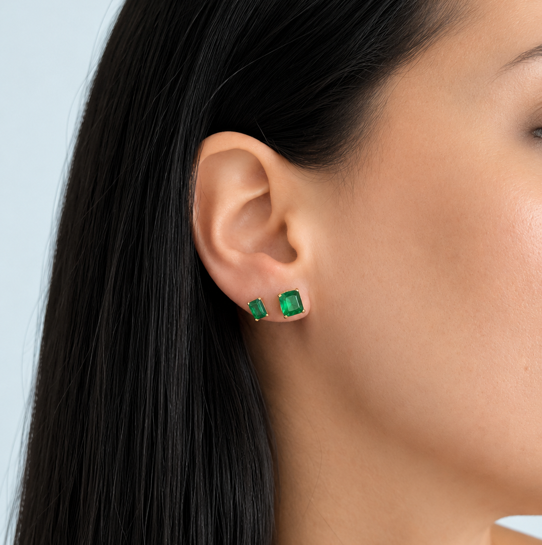 Woman wearing 14K Solid Yellow Gold Emerald Cut Green CZ Stud Earrings featuring vibrant emerald-green cubic zirconia gemstones in a classic four-prong setting, photographed on ear for size, fit, and everyday wear styling. | Laraquel Jewelry