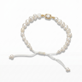 14K solid yellow gold adjustable bracelet with flat freshwater baroque pearls, white satin macramé cord, rectangular bezel cubic zirconia center, and gold end bead detail
