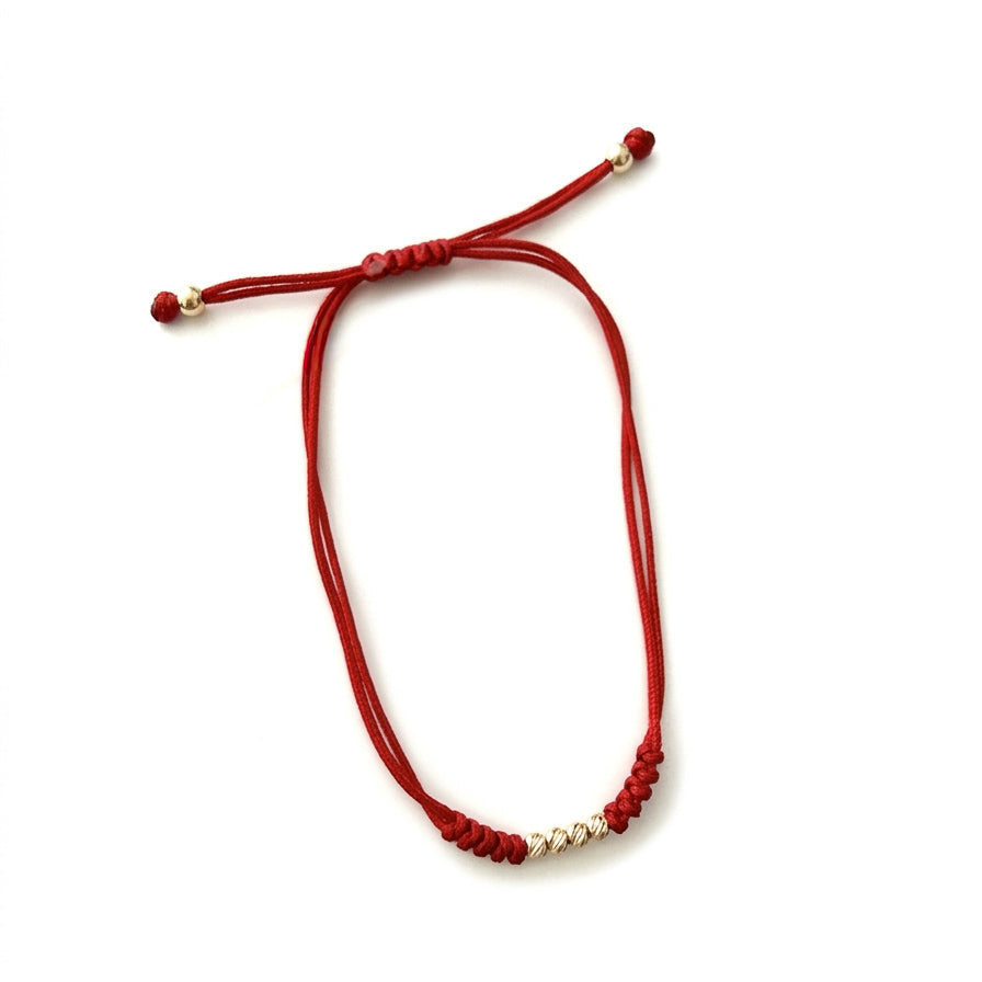 14K solid yellow gold adjustable red string bracelet with three D-cut gold beads on white background
